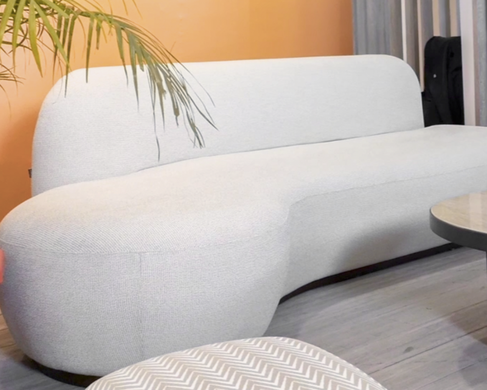 A cozy Luc Sofa in a light, textured fabric, styled in a warm and inviting room with a summer-inspired theme.